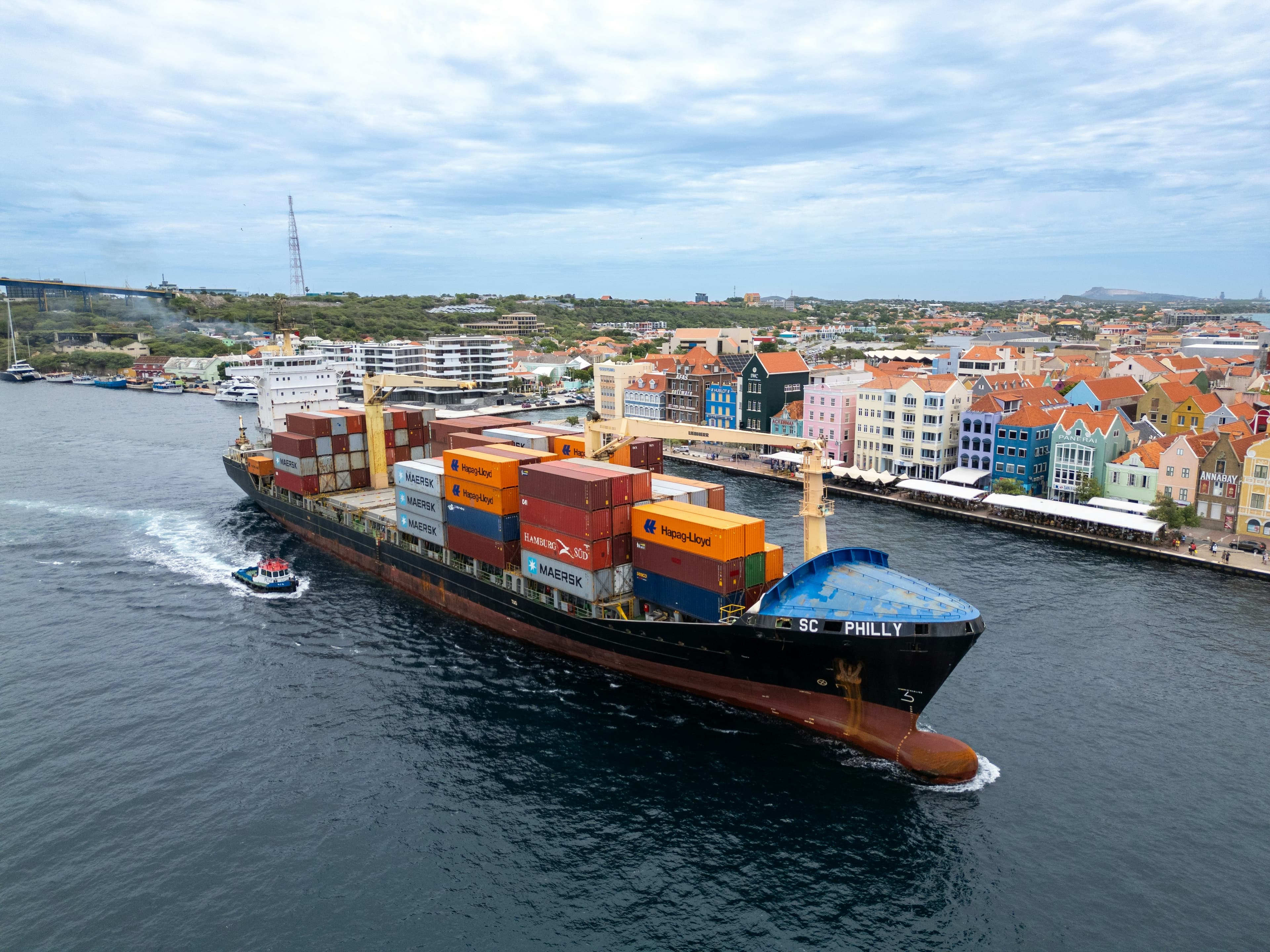 Container ship arriving in Willemstad harbor, Curaçao, with the colorful Handelskade waterfront behind it
